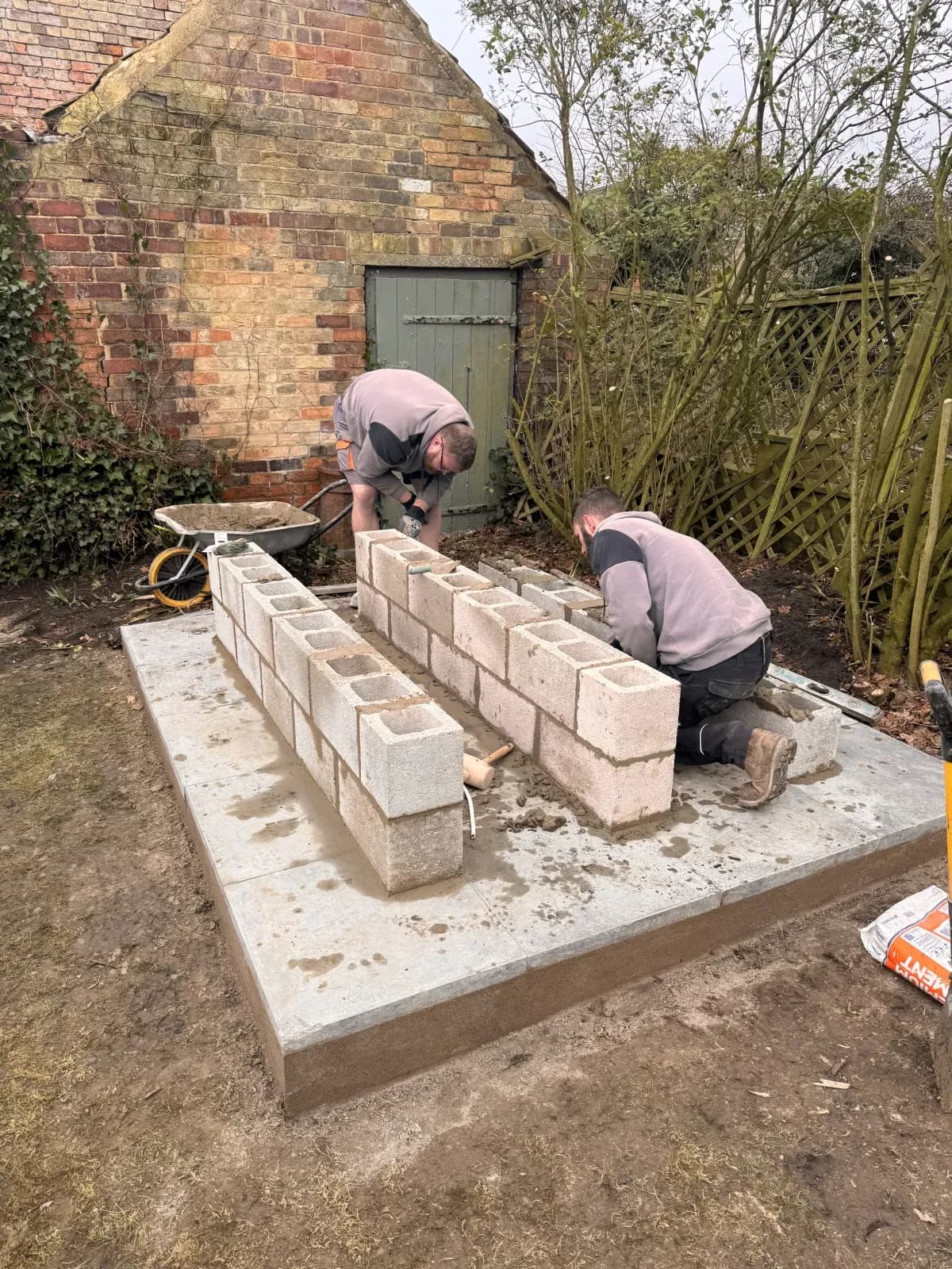 Engineers building a raised blockwork plinth for a domestic oil tank