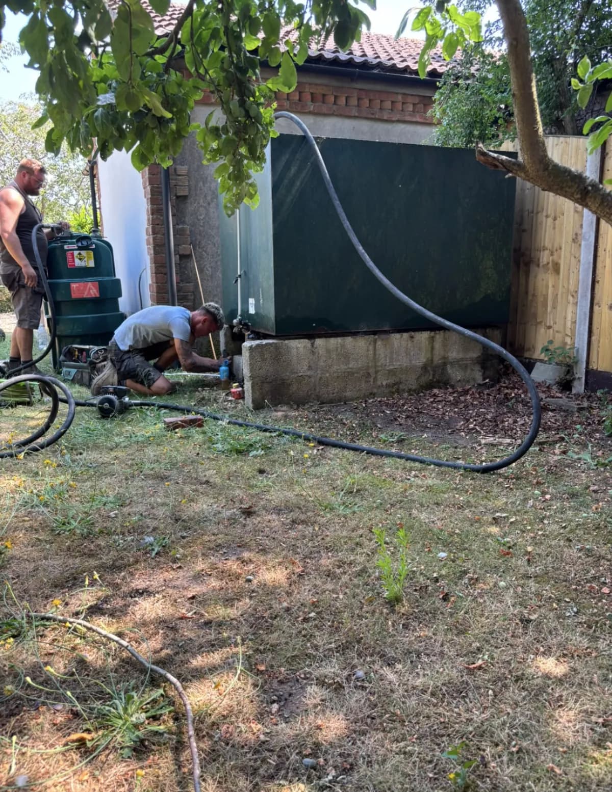 Engineers pumping oil from an old tank before disconnecting and removing it