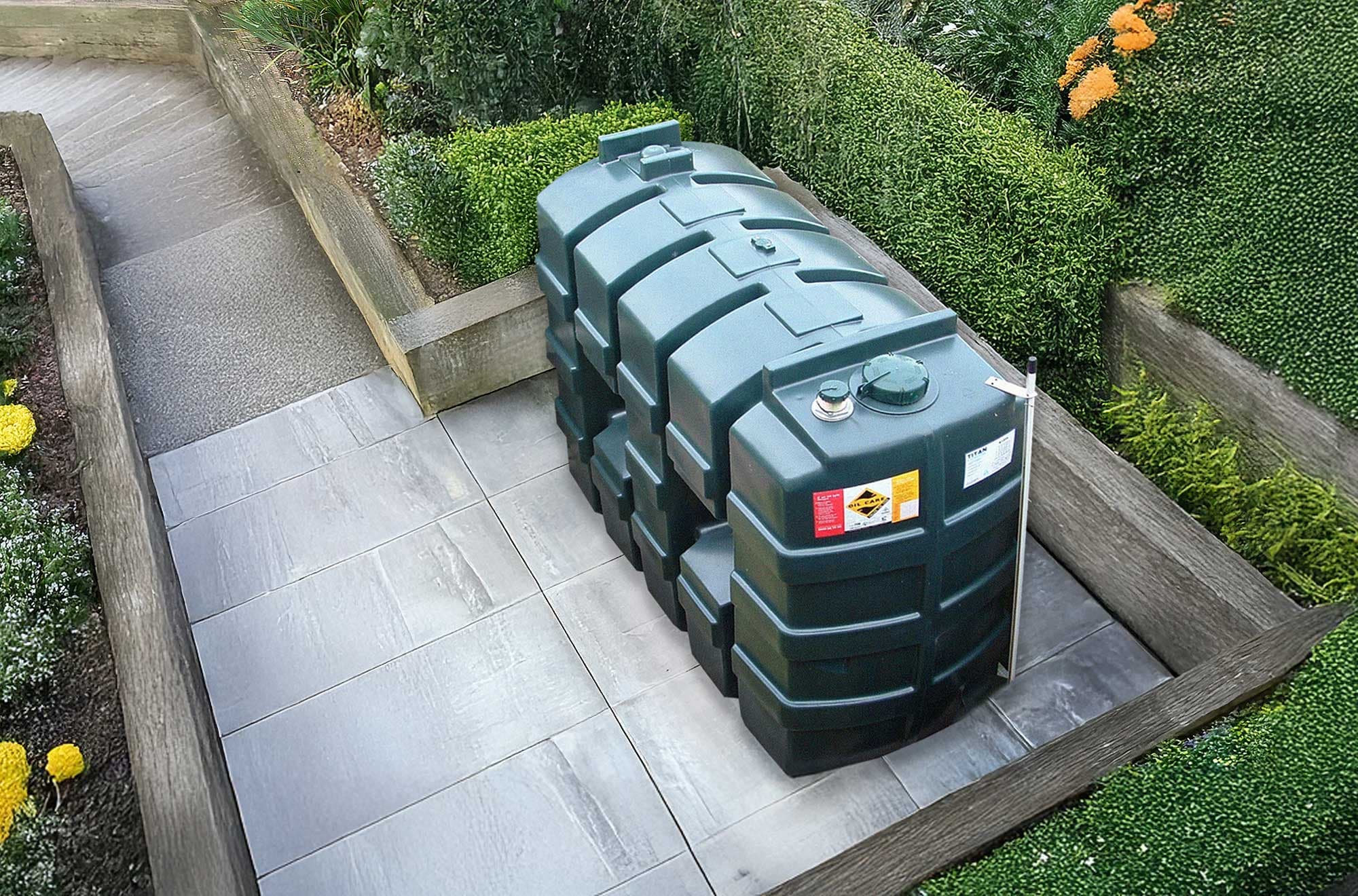 A newly installed green bunded oil tank sitting on a level paved base in a domestic garden