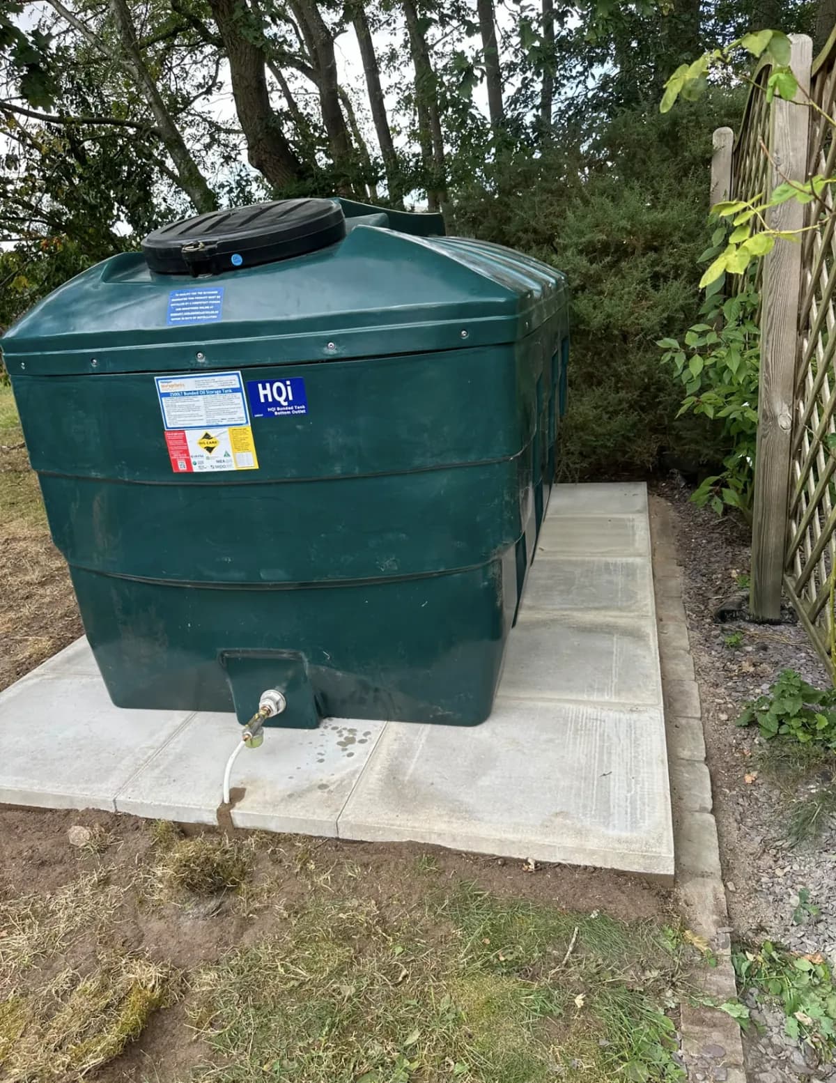 Green bunded domestic oil tank installed on a new garden slab base